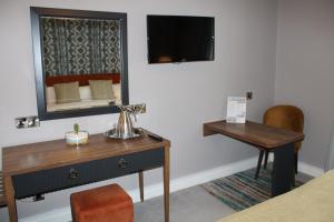 a room with a desk and a mirror and a table at Woodford Dolmen Hotel Carlow in Carlow