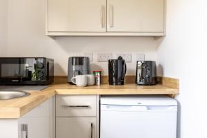 a kitchen with a counter top with a microwave and appliances at The Dunes - Room 12 in Rhosneigr