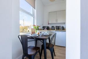 a kitchen with a table and chairs and a kitchen with white cabinets at The Dunes - Room 12 in Rhosneigr