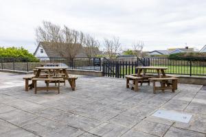 two picnic tables on a patio with a fence at The Dunes - Room 12 in Rhosneigr