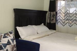 a bed with white pillows sitting next to a window at The Quiet Nest in Ruiru