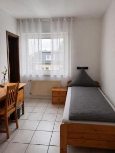 a bedroom with a bed and a desk and a window at Frühstückspension Stenbrock in Grevenbroich