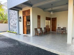a porch of a house with chairs and a table at The Ceylon Slate in Tangalle