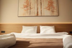 a bed with white sheets and pillows in a bedroom at Hotel & Restaurant HAREA in Suharekë