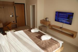 a bedroom with a large bed with a flat screen tv at Hotel & Restaurant HAREA in Suharekë