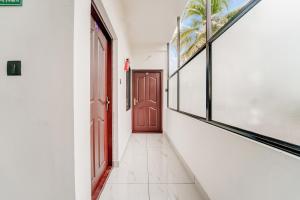 an empty hallway with a red door and windows at Hotel O HMT Colony Kochi Formerly Pullans Arcade in Cochin