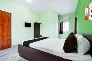 a bedroom with a bed with white sheets and green walls at Hotel O Bhubaneshwar Near ITER College in Bhubaneshwar
