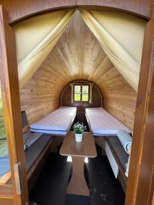 a room with two beds in a wooden cabin with a table at Campingplatz Weserterrassen Polle in Polle