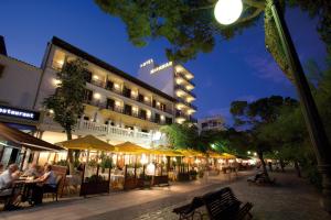 un hotel con gente sentada en las mesas frente a él en Hotel Miramar Mallorca en Puerto Pollensa