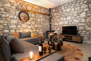 a living room with a stone wall with a couch and a tv at Kösedere Stone Houses in Karaburun