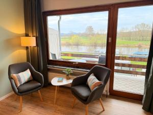 two chairs and a table in a room with a large window at Campingplatz Weserterrassen Polle in Polle +8 photos