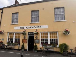 a yellow building with a sign that reads the oak house at Oak House Hotel in Axbridge