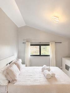 a white bedroom with a large bed with towels on it at Vista Sol in Bicas
