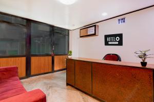 an office with a reception desk and a red couch at Super Hotel O Howrah Railway Station in Kolkata