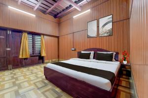 a bedroom with a large bed in a wooden wall at Hotel O Kallar Vattiyar Waterfalls Munnar in Munnar