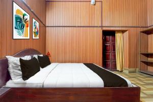 a bedroom with a large bed with a wooden wall at Hotel O Kallar Vattiyar Waterfalls Munnar in Munnar +35 photos