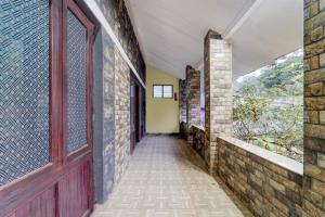 an empty hallway with a red door and a brick wall at Hotel O Kallar Vattiyar Waterfalls Munnar in Munnar
