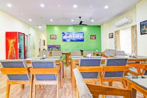 a dining room with tables and chairs and a green wall at Super OYO Townhouse Dwarakanagar Near Gurudwara in Visakhapatnam