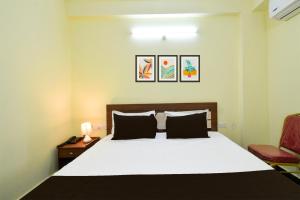 a bedroom with a white bed and a red chair at Super Collection O Godavari Kompally in Hyderabad