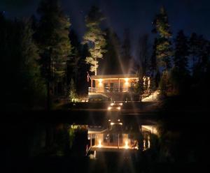 a house with lights on the water at night at AVOTUPJi in Plānupe +27 photos