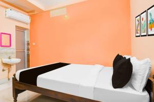 a bedroom with a white bed with an orange wall at Hotel O Dakshin Dwar Formerly Radha Krishna Niwas in Puri +39 photos