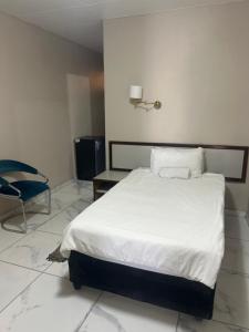 a bedroom with a white bed and a chair at Caponero accommodation conference in Welkom