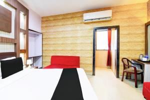 a bedroom with a bed and a red chair at Collection O Karaya Road Formerly Hotel New Diamond in Kolkata +36 photos