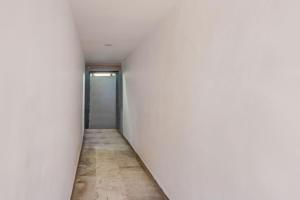 a corridor of an empty room with white walls and a door at Super Hotel O Chowrasta Near Congress Bhavan in Warangal