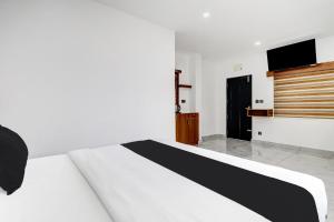a bedroom with a white bed and a flat screen tv at Collection O Munnar in Munnar +39 photos