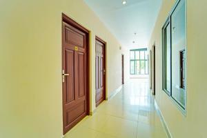 a hallway with two wooden doors and a tile floor at Super Collection O Kureepuzha Kollam in Kollam