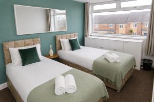 a bedroom with two beds and a window at Spacious, Modern and stylish three bedroom home , perfect for work , leisure and contractors ,5 mins walk to Newcastle city Center, Newcastle stadium and Newcastle University, Free parking Fast WiFi, conveniently located both short stay and long stays in Newcastle upon Tyne +4 photos