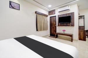 a room with a bed and a flat screen tv at Super Hotel O Vijayawada Near Railway Station in Vijayawāda +35 photos