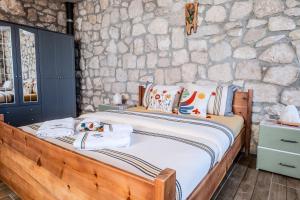 a bed in a room with a stone wall at Kösedere Stone Houses in Karaburun