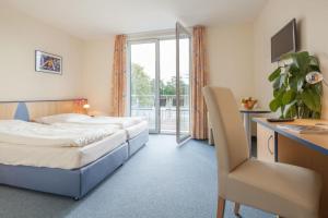 a hotel room with two beds and a desk at Tunici Team Hotel in Hamburg