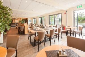 a dining room with tables and chairs and windows at Tunici Team Hotel in Hamburg