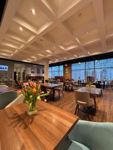 a dining room with tables and chairs and a vase of flowers at Hampton By Hilton Gdansk Old Town in Gdańsk