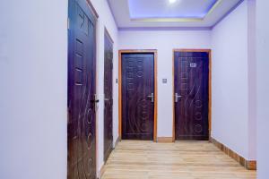 a hallway with three wooden doors in a room at Hotel O Garchuk Market Formerly Trendz Stay in Guwahati