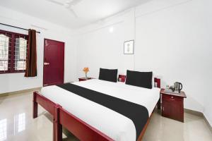 a bedroom with a large bed with a red door at Super Hotel O Sultan Bathery Formerly Bluevalley in Wayanad +40 photos