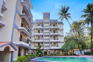 an apartment building with a swimming pool and palm trees at Super Townhouse Calangute Formerly Hotel Horizon in Goa