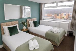 a hotel room with two beds and a window at Spacious, Modern and stylish three bedroom home , perfect for work , leisure and contractors ,5 mins walk to Newcastle city Center, Newcastle stadium and Newcastle University, Free parking Fast WiFi, conveniently located both short stay and long stays in Newcastle upon Tyne