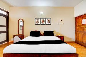 a bedroom with a large white bed with black pillows at Super Townhouse Calangute Formerly Hotel Horizon in Goa +67 photos