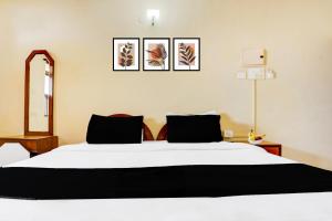 a bedroom with a white bed with three pictures on the wall at Super Townhouse Calangute Formerly Hotel Horizon in Goa