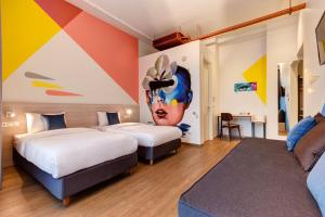 two beds in a room with a painting on the wall at Colors Urban Hotel Thessaloniki in Thessaloniki