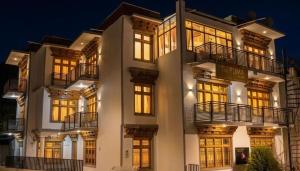 a large white building with lit windows at night at The Puma house in Leh
