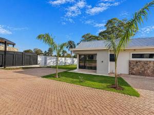 a house with two palm trees in front of it at 19 On Bay Noakes in Harare