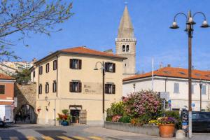 ein Gebäude mit einem Uhrturm und einer Kirche in der Unterkunft New Hotel Dulcinea in Muggia