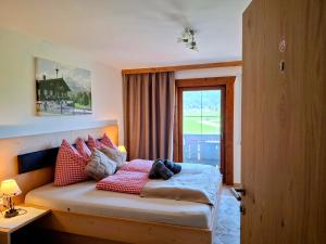 a bedroom with a bed with red pillows and a window at Lampererhof in Sankt Johann in Tirol