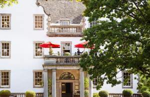 a white building with a balcony with red umbrellas at Prestonfield House in Edinburgh