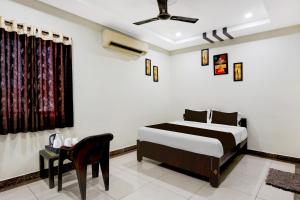a bedroom with a bed and a chair and a table at OYO Hotel O Benz Circle Vijayawada in Vijayawāda
