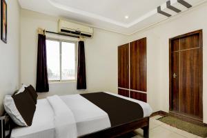 a bedroom with a large bed and a window at OYO Hotel O Benz Circle Vijayawada in Vijayawāda +41 photos